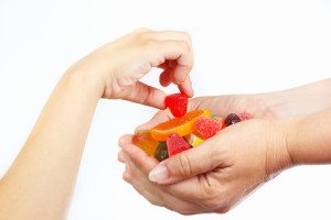 Child hand takes the jelly and sweets from hands her mother close up