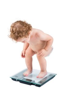 Very funny baby watching her weight, isolated on white